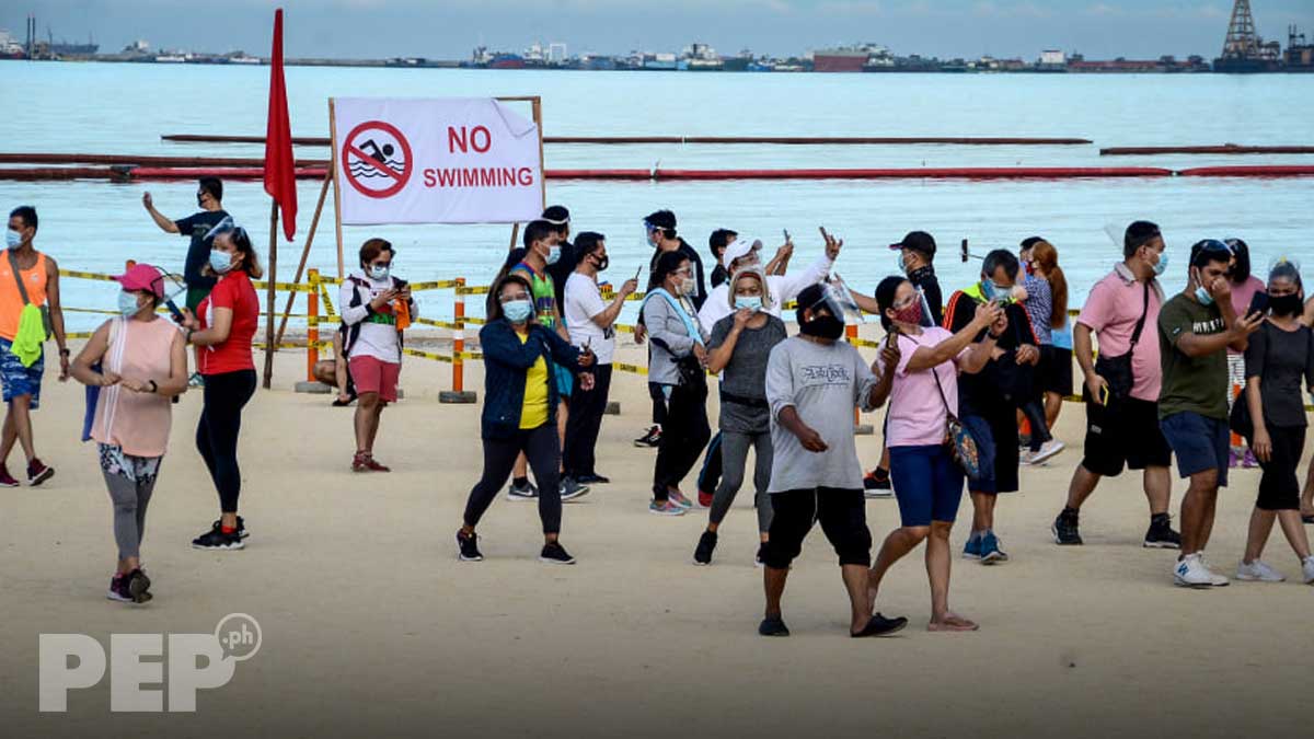 Manila residents walk on dolomite sand covered portion of rehabilitated Manila Bay.