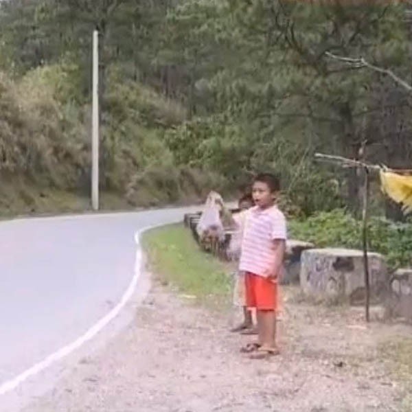 A screencap of Jessie Almoza peddling mushrooms on a road in Benguet