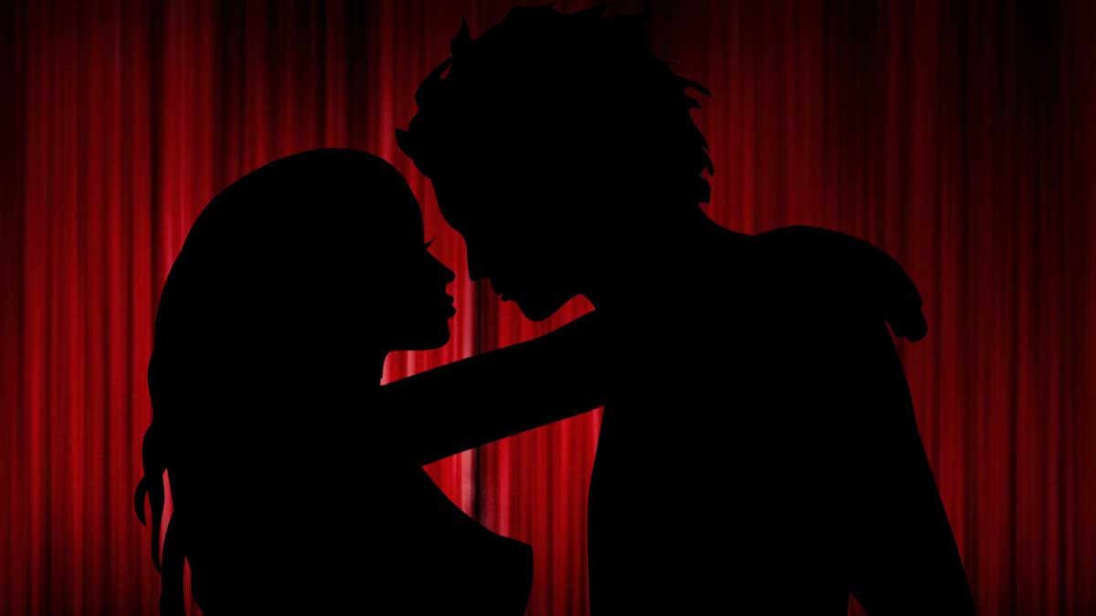 Silhouette of a woman and man about to kiss, set against a red curtain background.